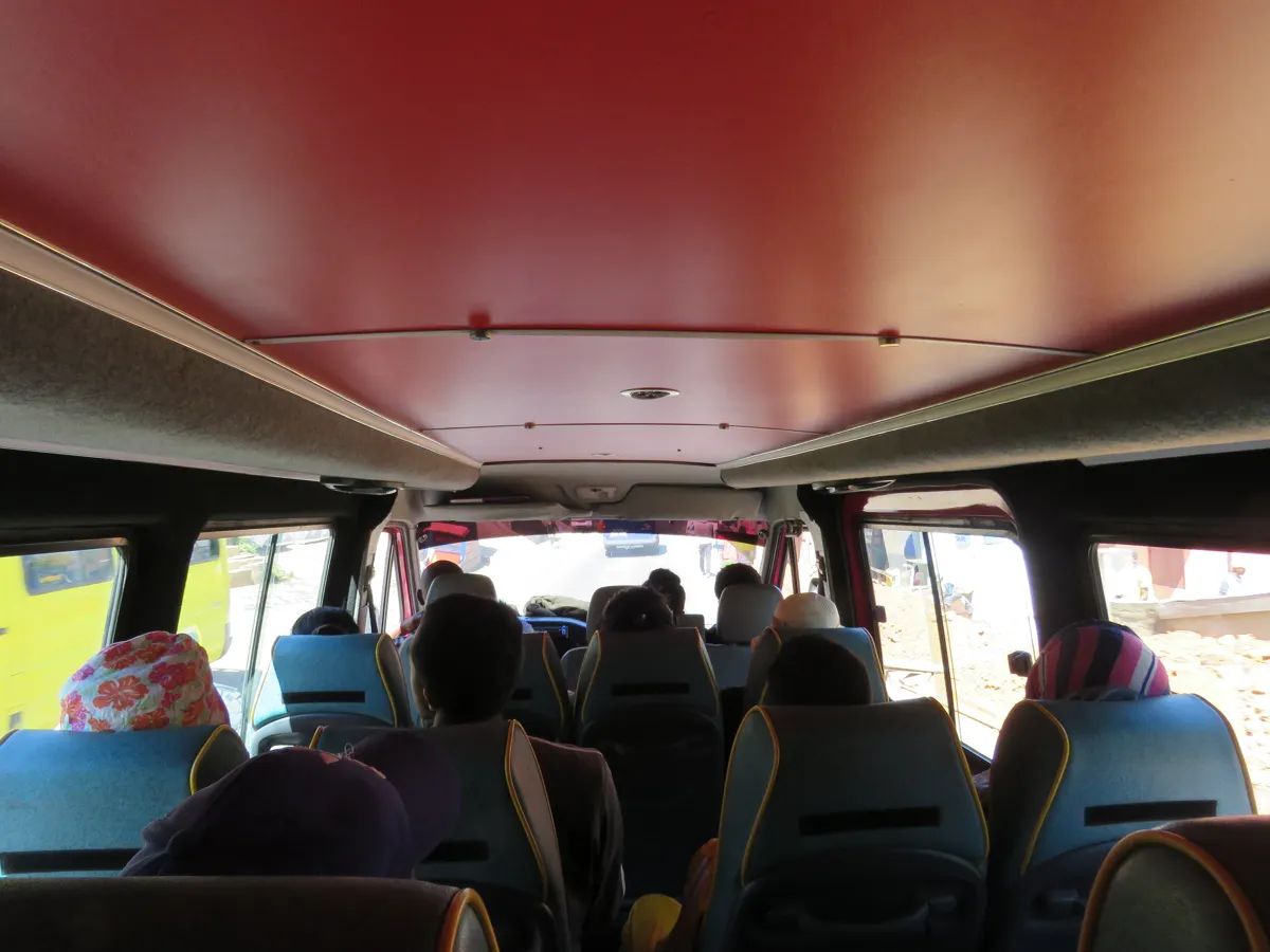 Vue depuis l’arrière d’un minibus à Antananarivo, avec passagers et sièges sans publicité